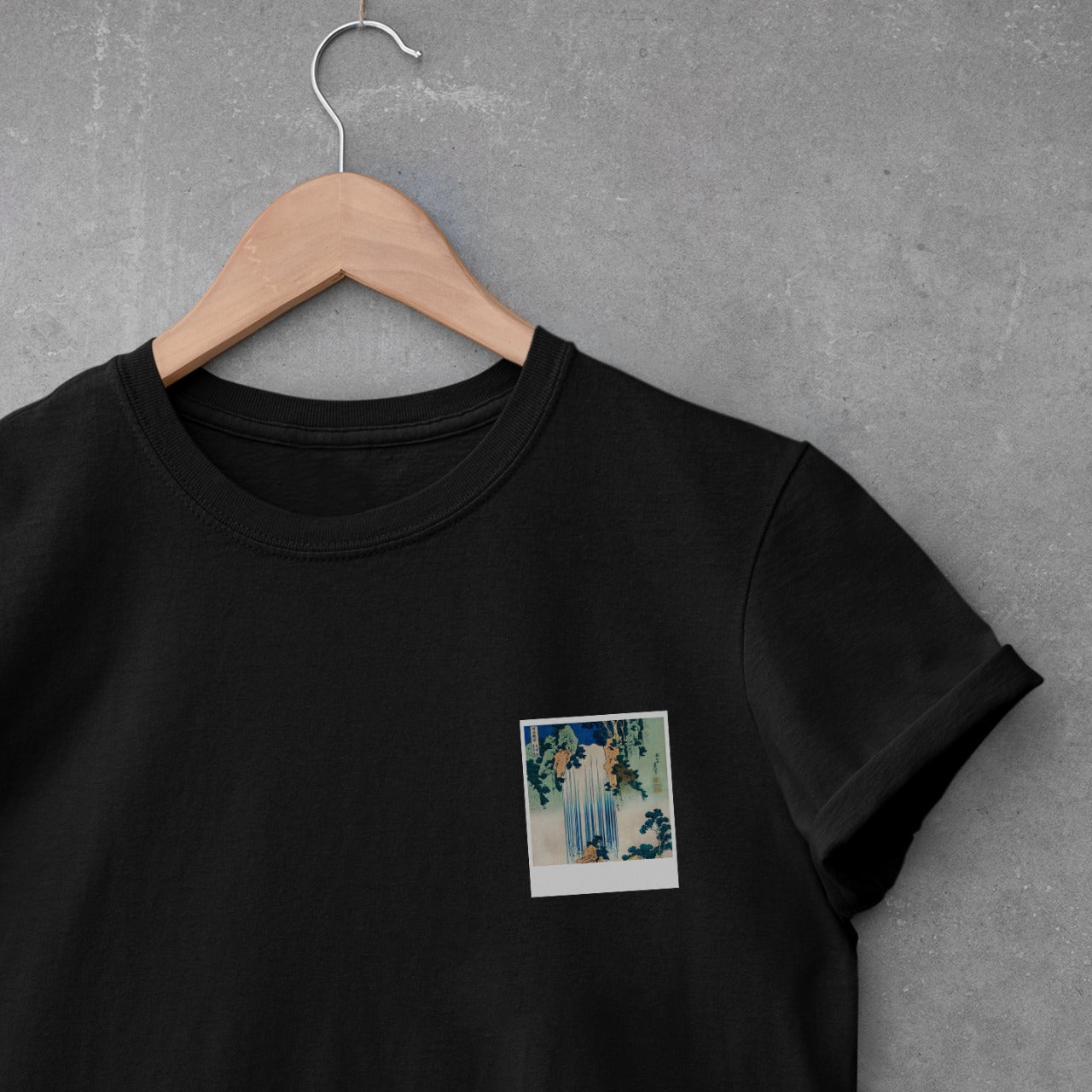 Japanese waterfall and foliage polaroid on black hanging t-shirt.