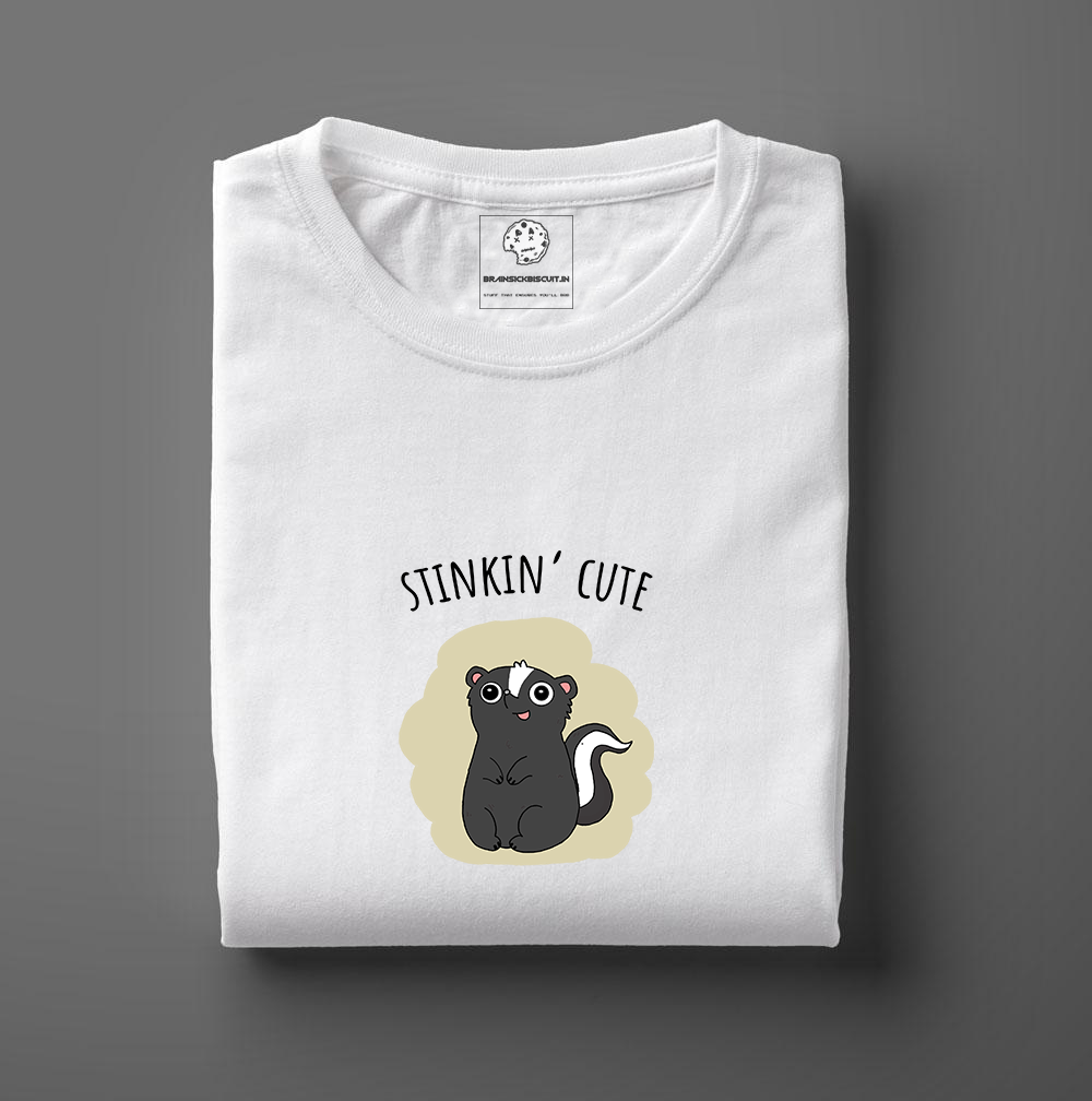 cute black skunk with stinkin cute on folded white t-shirt.